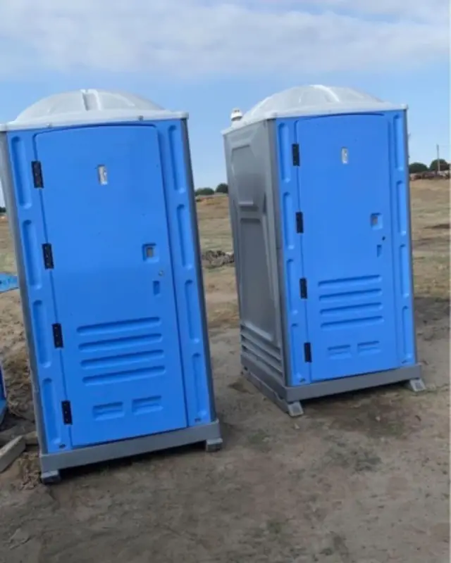 Two blue porta potties on a sunny jobsite