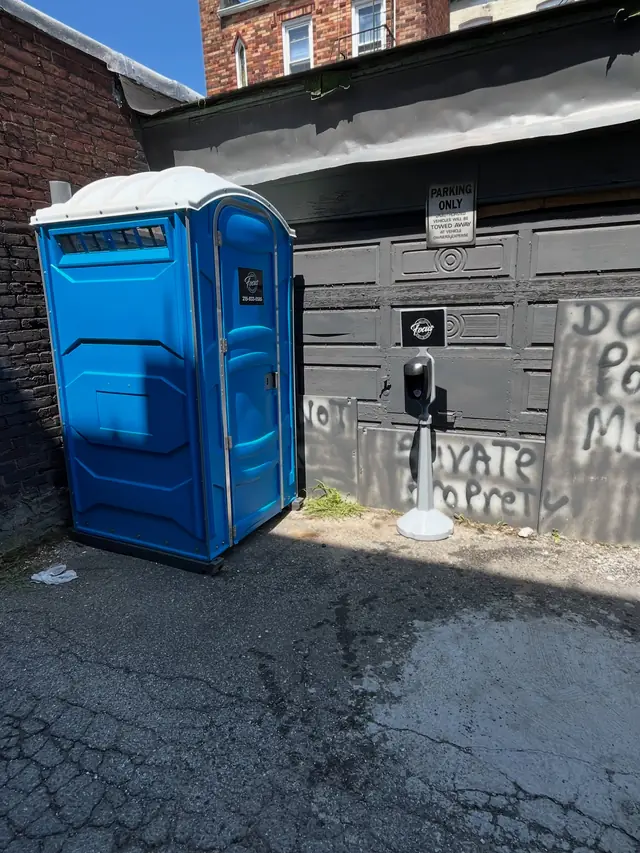 Blue porta potty placed beside a house